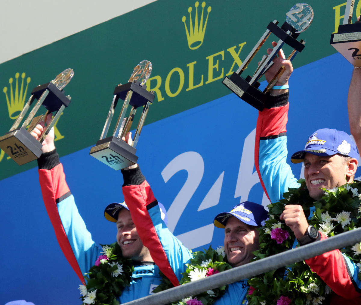 The 1st placed GTE Am crew, Henrique Chaves, Ben Keating & Marco Sorensen (Aston Martin Vantge AMR -33) celebrate their trophies on the podium at the 2022 Le Mans (54281398265).jpg